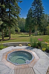 an outdoor jacuzzi with a concrete surround and a deck plus a garden view is a lovely idea for relaxation and to feel calm