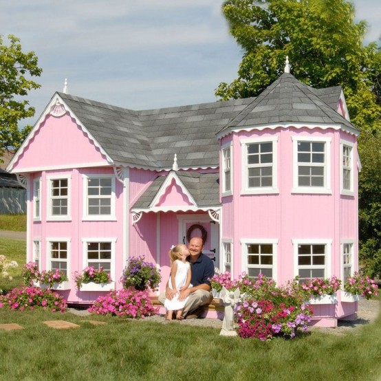a light pink kids' playhouse with two floors and pink blooms planted around is a whole real mansion for a little kid