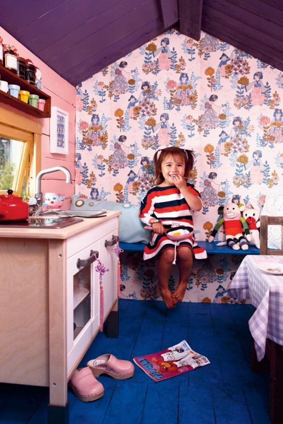 a colorful kids' playhouse with a purple ceiling, a bright blue floor, a neutral kitchen and a dining table with a checked tablecloth