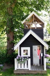 a black and white Nordic kids’ playhouse with a small deck and potted blooms is a cool idea for a Scandi-inspired garden