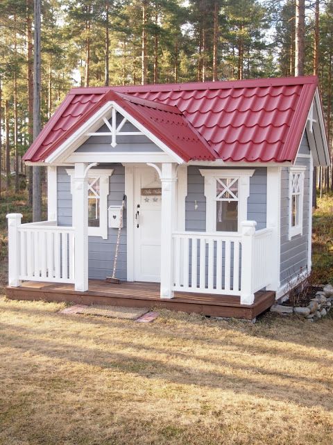 a cool small kids' playhouse in grey and white, with a red roof, a small porch is a cute and lovely rustic idea
