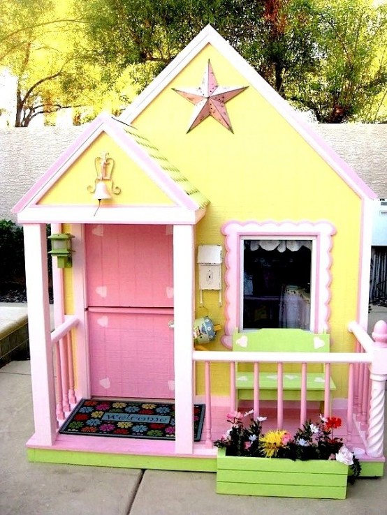 a super colorful kids' playhouse with yellow walls and a pink door, a green bench and a planter with greenery is fun and cool