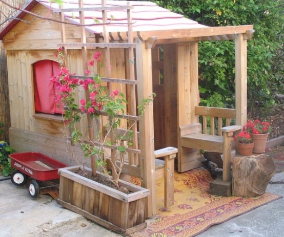 a stained kids' playhouse with potted blooms, with colorful curtains looks very rustic and very cozy, with rustic stuff around it