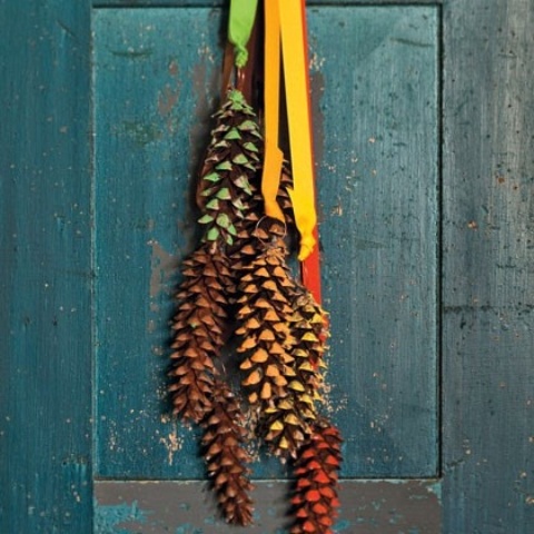 Here is a cool idea for a colorful DIY front door decor that doesn't require a wreath form. To make this cool door hanger you'll need a bunch of pinecones, several pieces of silk ribbon and some paint.