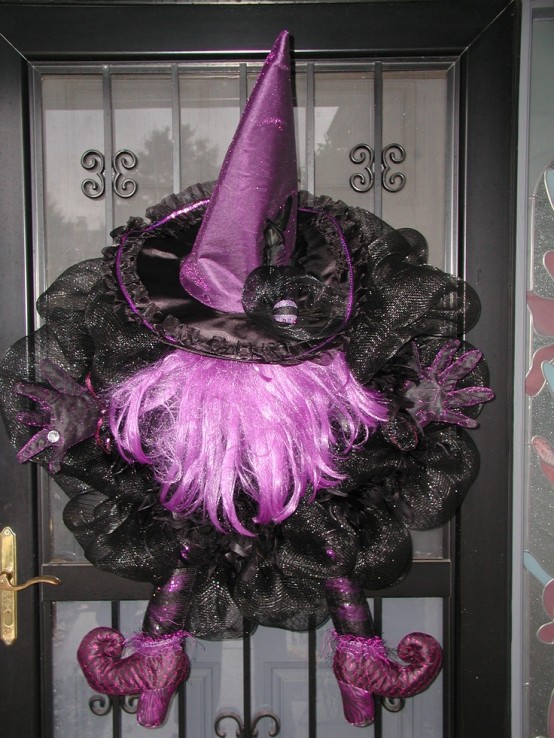 a bold black and purple Halloween decoration of black mesh ribbons, a purple witch hat, legs and some hair is a unique alternative to a usual Halloween wreath