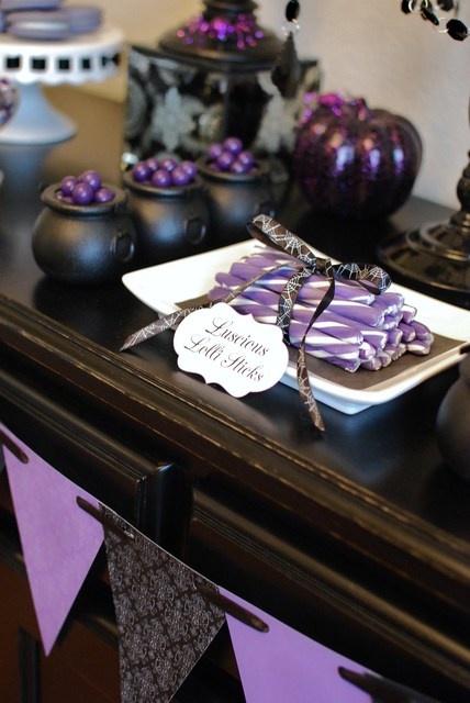 a black and purple Halloween sweets table with various candies, sweets, desserts and pumpkins is a stylish and cool idea