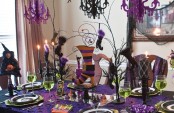 a super bright green, purple, black and orange Halloween tablescape with witches’ legs, hats and other catchy decor