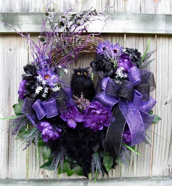 a unique and bold Halloween wreath with purple and lilac bows, with an owl, fake blooms, foliage and branches is a statement