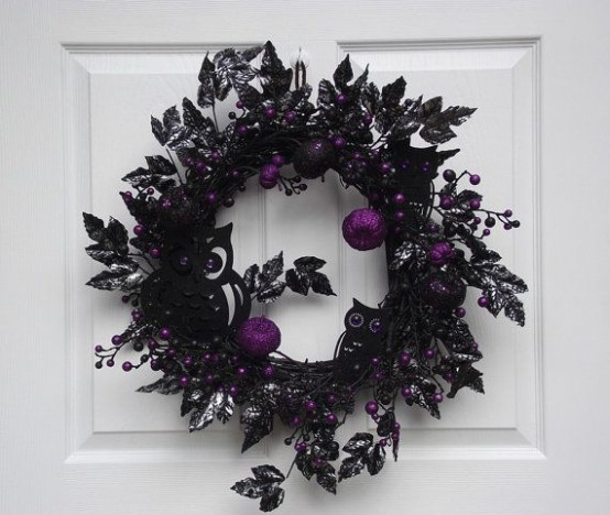 a super elegant and moody black and purple Halloween wreath with berries, apples, silhouette owls and mcuh other stuff looks refined