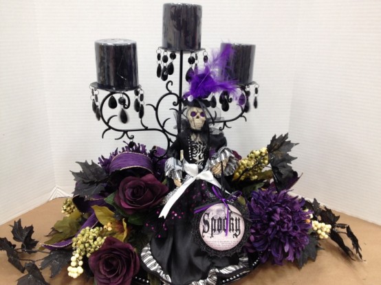 a refined Halloween decoration of a black candelabra, black candles, purple feathers and blooms and lots of other stuff for decorating