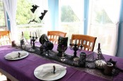 a purple Halloween tablescape with black candelabras, skulls, candles and other decor is a refined idea for Halloween