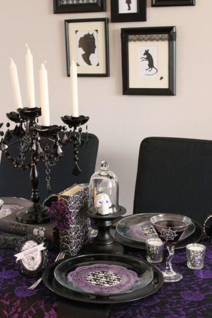 a sophisticated black, white and purple Halloween tablescape with a black candelabra, white candles, skulls, glasses and other stuff