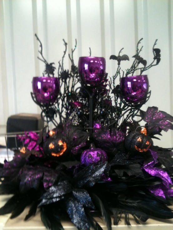 a dramatic Halloween decoration or centerpiece of faux black foliage, feathers, branches with bats, purple candleholders and skulls