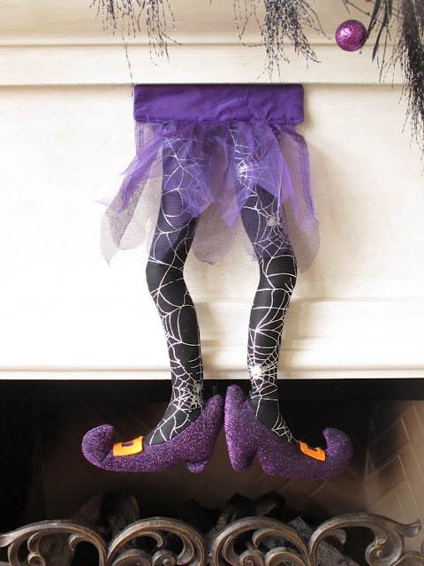 black and purple spiderweb witch's legs hanging over the fireplace is a very catchy and cool Halloween decor idea