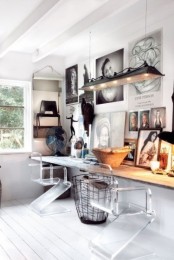 a white modern and rustic home office with a rough wood floating desk, an industrial pendant lamp, a gallery wall and ghost chairs