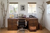 a neutral rustic home office with a wooden desk, tree branches, a jute rug, burlap shutters and a stylish mid-century modern chair