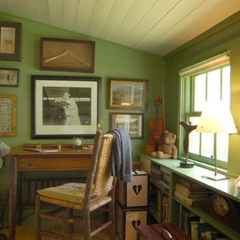 a rustic home office with green walls, vintage stained and painted furniture, a gallery wall and some decor and lamps