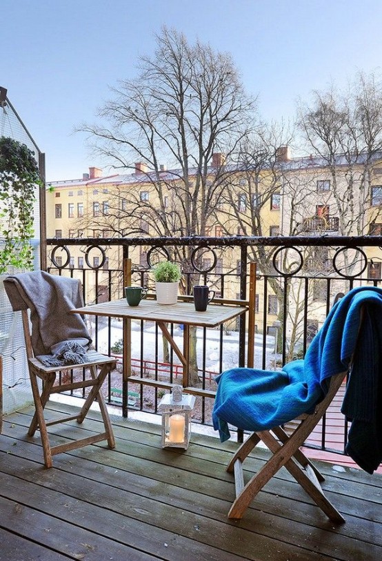 a relaxed Scandinavian balcony with stained folding furniture, a candle lantern and potted greenery is amazing