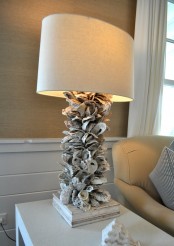 a chic table lamp with a base of seashells and a usual shade catches an eye and looks very sea-inspired