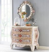 a white sideboard clad with various seashells and a matching mirror on the wall for a catchy and bold entryway of a beach home