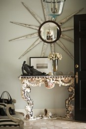 a refined vintage-inspired console table clad with seashells and pebbles looks statement-like and cool