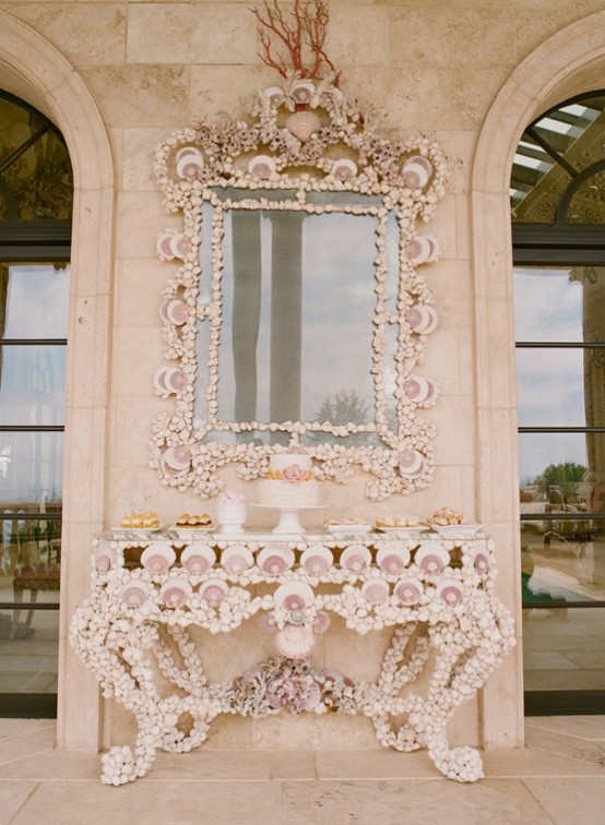a vintage console table and a matching mirror frame fully clad with seashells of various sizes look very bold and cool