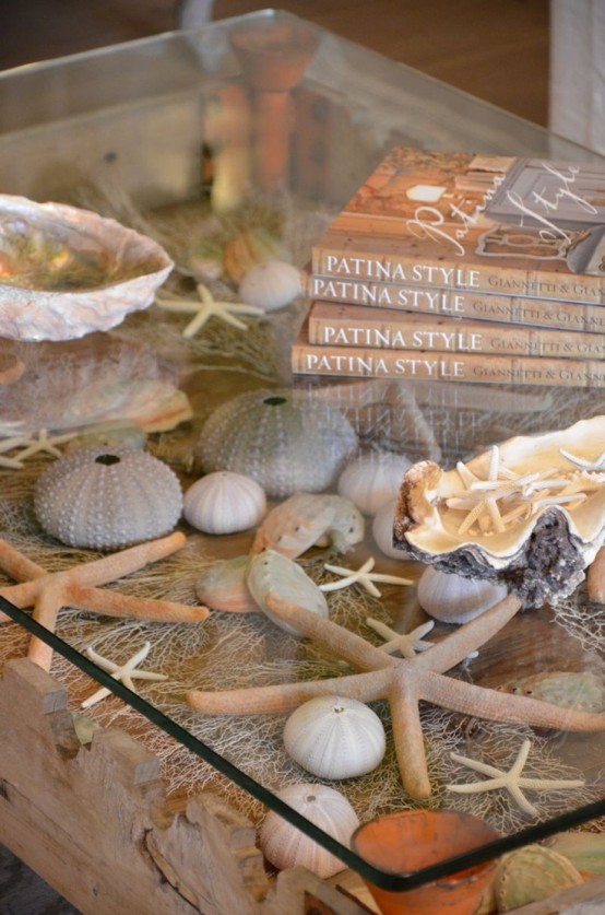 a beautiful sea-inspired coffee table with a glass tabletop and sand, seashells, urchins and corals inside for a beautiful look