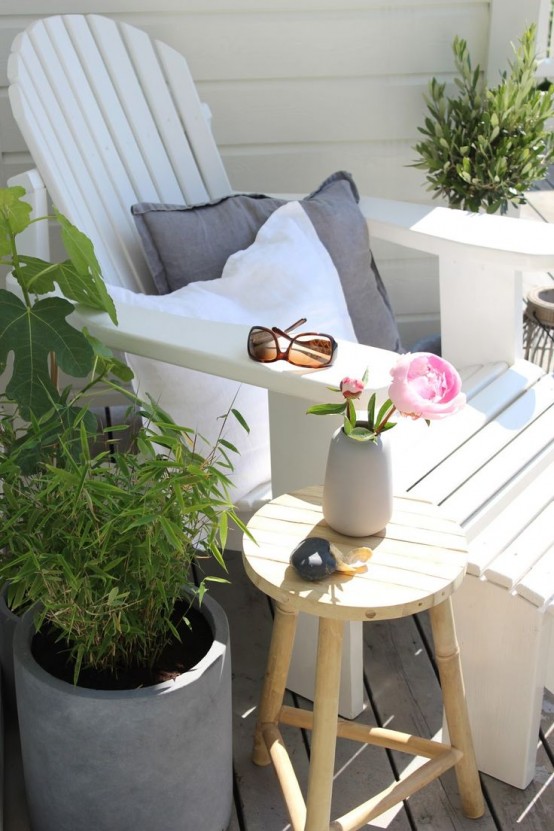 a tiny cozy terrace nook with a whiet lounger, a stool and potted greenery on the sides