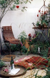 a boho vintage terrace with forged furniture, boho textiles, lots of candles and a cute picnic setting