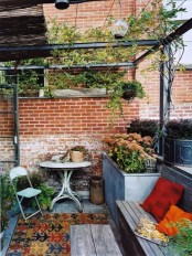 a small shabby chic terrace with rustic and vintage furniture, boho rugs and potted greenery and blooms