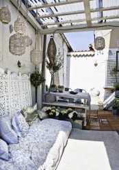 a neutral boho chic terrace with some vintage furniture, rattan lanterns, potted plants and blooms