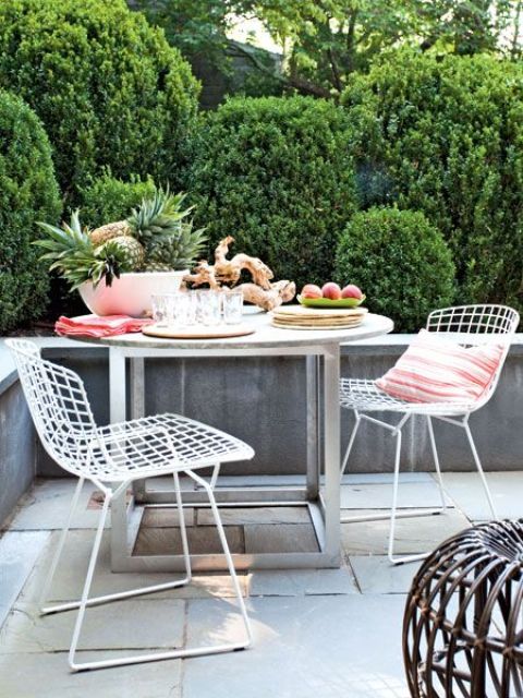 a small contemporary terrace with an eating space, wire chairs, a metal and wood table and a rattan ottoman