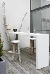 a small minimalist terrace with an old tree and a sleek white countertop that can be used as a bar counter or a desk