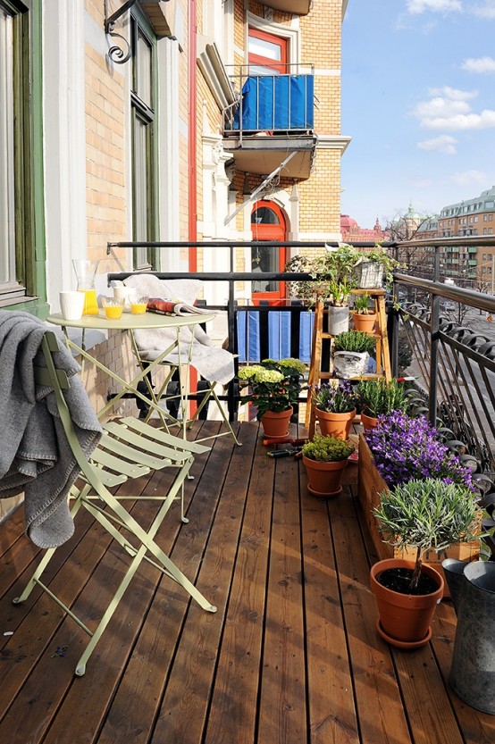 lots of greenery and bright blooms in wooden and terra cotta pots will make your balcony feel like spring and a bit rustic