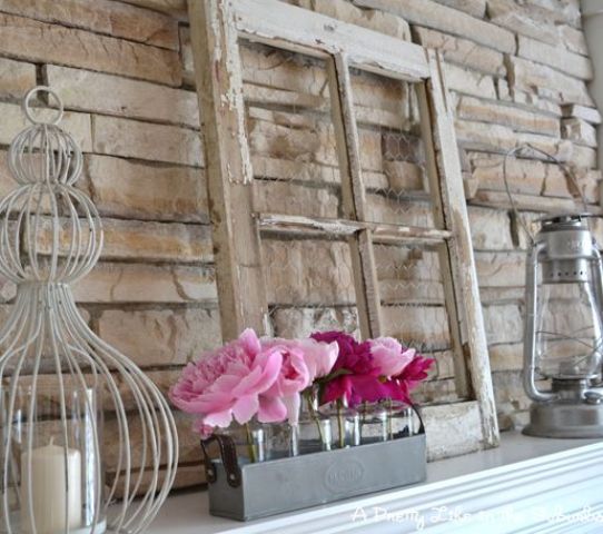 a summer mantel with a vintage window, candle lanterns, an arrangement of bright pink blooms