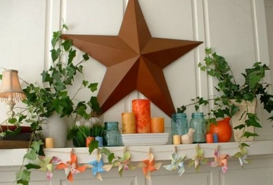 a bright summer mantel with a star, potted greenery, colorful candles and jars plus a paper banner