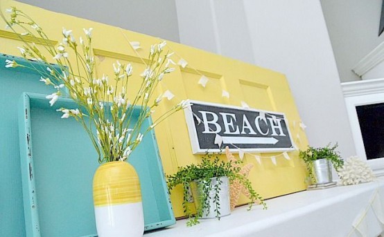 a colorful summer mantel in turquoise and yellow, with potted greenery, a sign and blooming branches