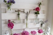 a blooming summer mantel with a white pallet, bright pink blooms and white candle lanterns