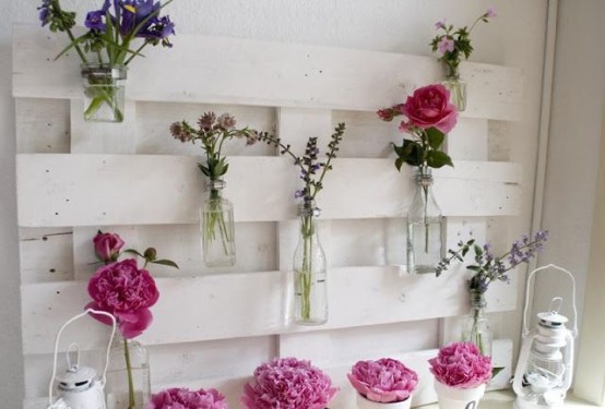 a blooming summer mantel with a white pallet, bright pink blooms and white candle lanterns