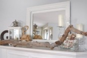 a beachy summer mantel with candles, lanterns, driftwood, rope and a large jar with shells