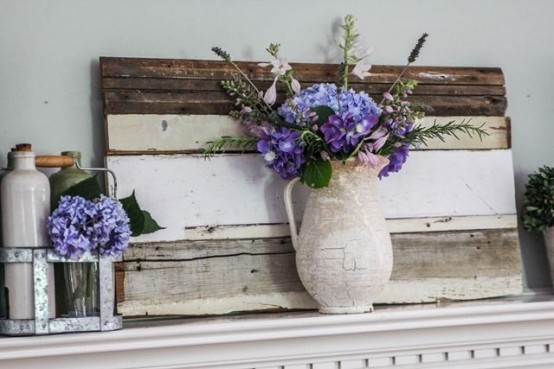 a cheerful summer mantel with pallets and bright purple blooms in vases and bottles