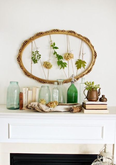 an elegant summer mantel with a frame with greenery and blooms, vintage books, bottles and driftwood
