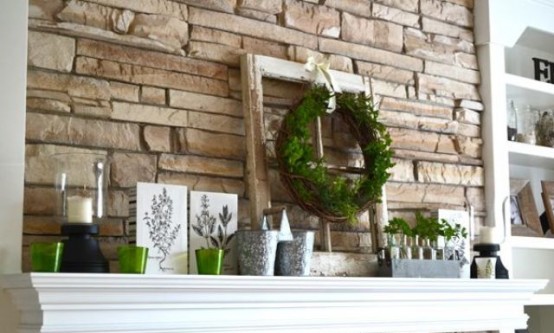 a rustic summer mantel with a greenery wreath and potted greenery, buckets, candle holders and posters