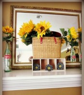 a bright summer mantel with sunflowers, a basket and a large mirror to maximize the light
