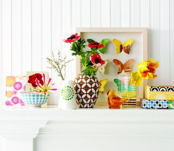 a colorful and bright summer mantel with blooms, vases, bird figurines and bright wrapped gifts