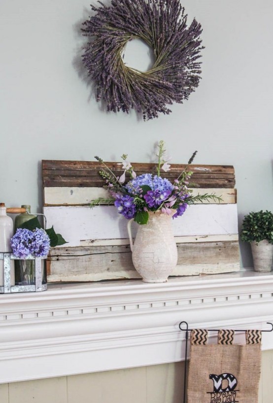 a rustic summer mantel with a lavender wreath, a pallet and purple blooms in vases and jars