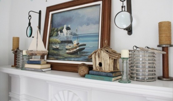 a seaside mantel with a sea artwork, boats, a bird house and nautical lanterns and candles