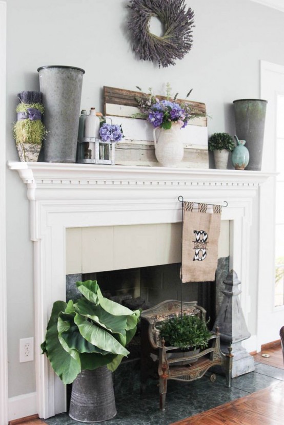 a rustic summer mantel with a shabby pallet, metal buckets, candles, potted greenery and blooms in vases