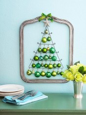 a beautiful Christmas tree wall art with a metallic frame, a silver star and a Christmas tree composed of green and yellow ornaments is a creatve alternative to a usual tree
