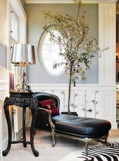 a sophisticated potted tree decorated with gold bells and red ornaments is a refined and chic idea for a holiday space
